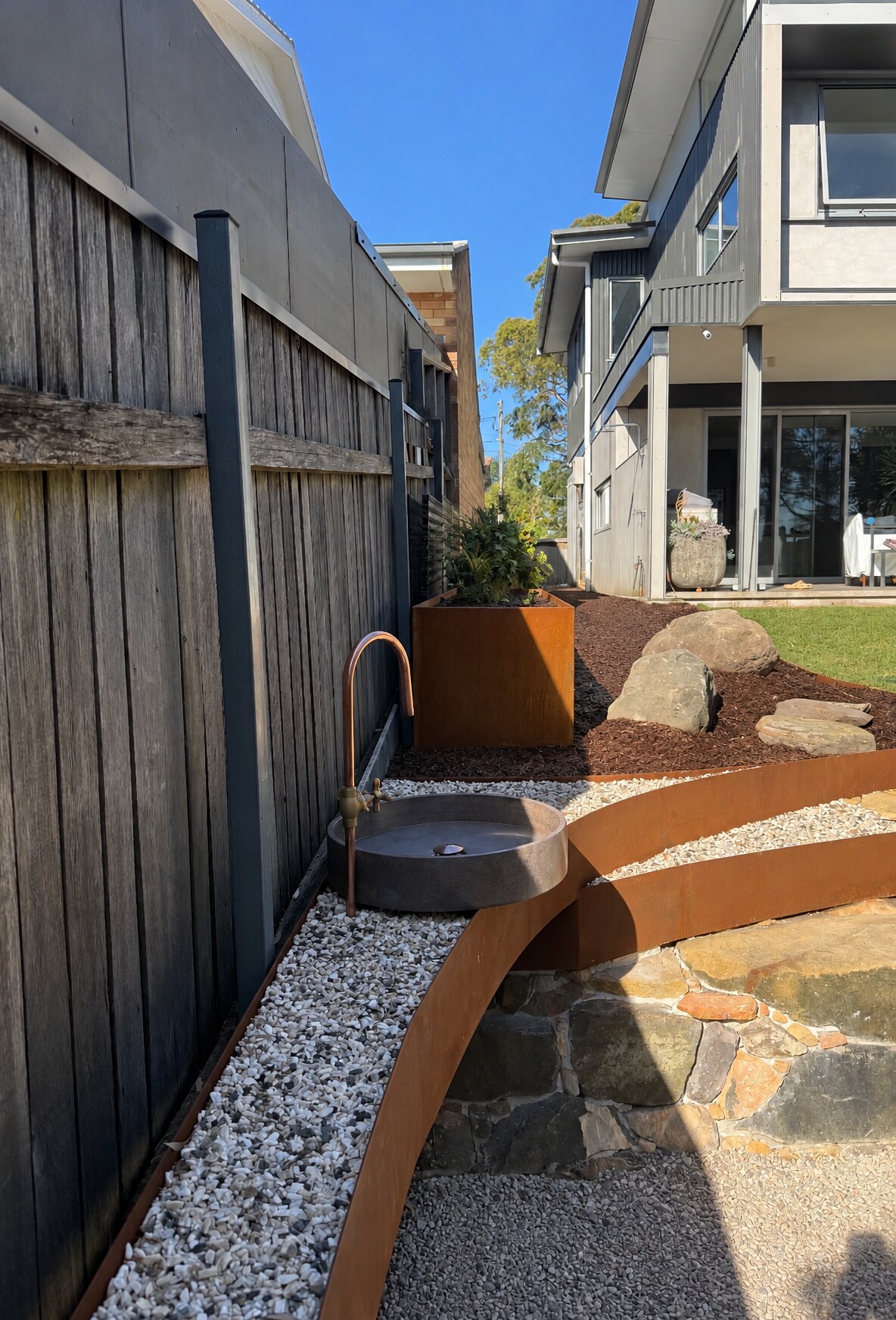 Tiered Corten steel edging with stone basin & copper tap